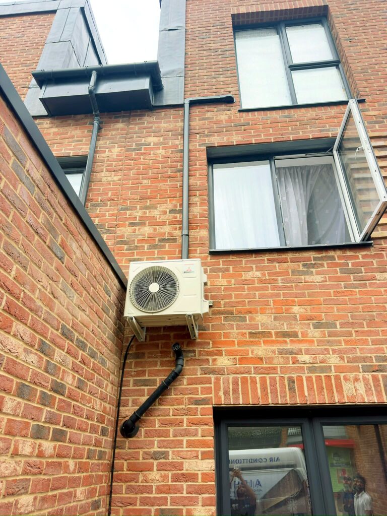 Air conditioning condenser mounted on wall brackets on a townhouse